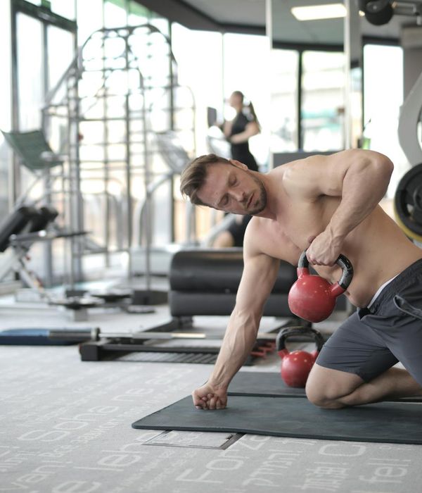 Man doing functional strength exercises in a modern dark gym environment.